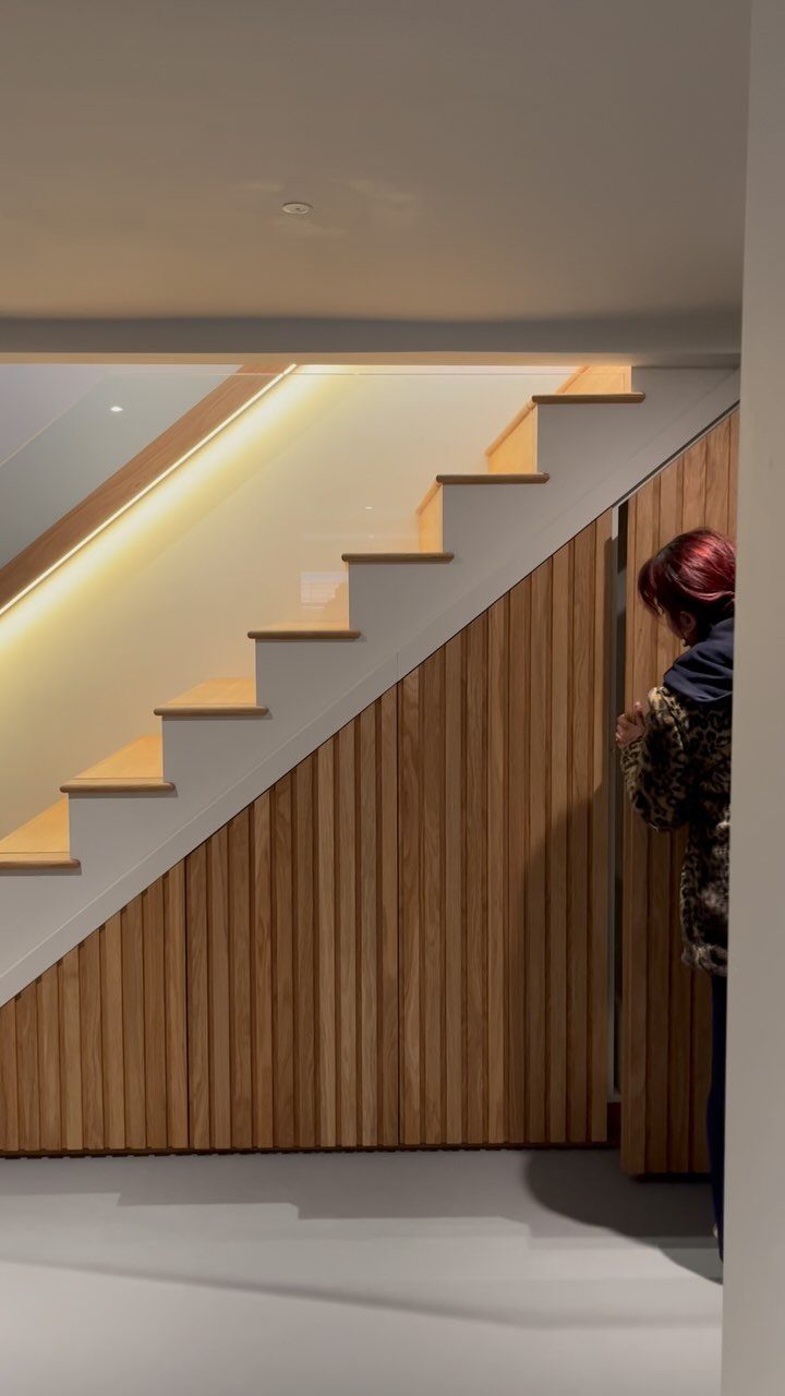 Modern wooden staircase with integrated storage cabinets built into the space underneath the stairs.