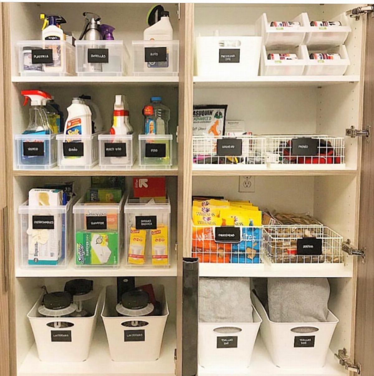 White storage closet shelves filled with organized bins and baskets containing various household supplies and cleaning products.