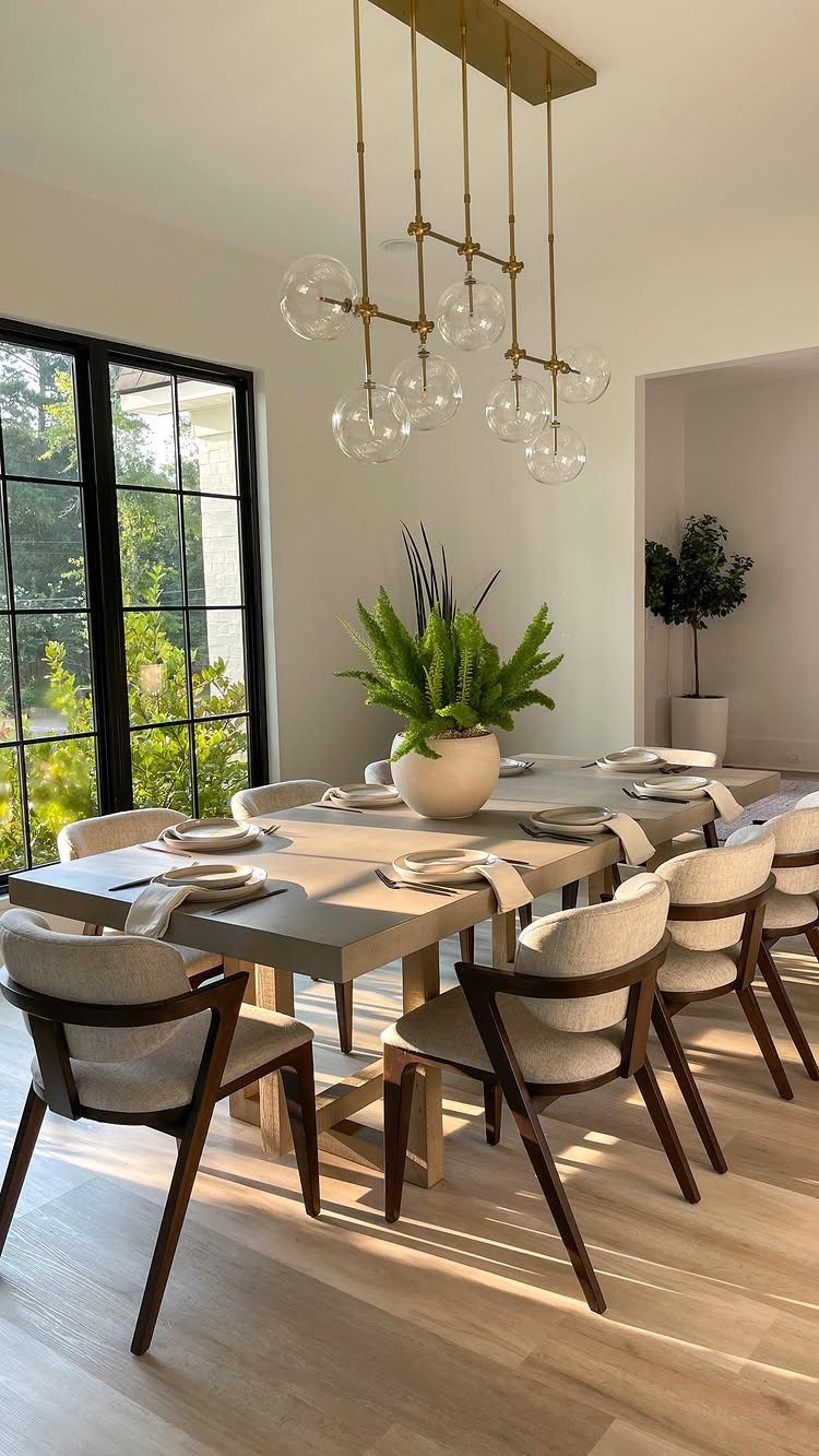A contemporary dining room with a wooden table, white chairs, and large black-framed windows.