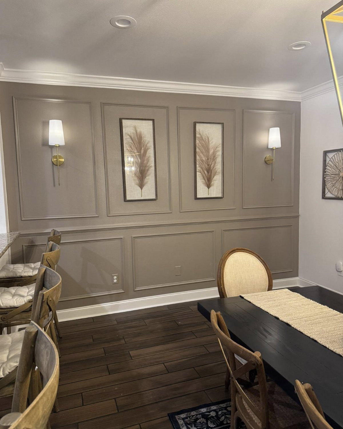 Dining room with taupe wainscoted walls, botanical art, and a dark wood table.