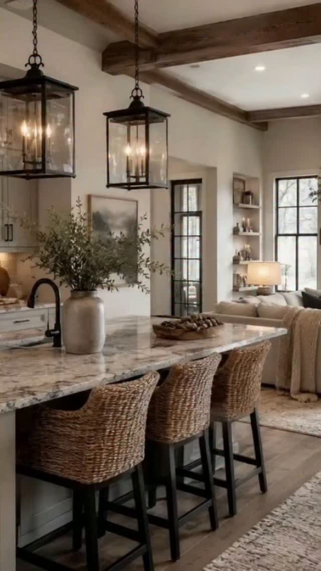Kitchen island with marble countertop, wicker bar stools, and black lantern pendant lights hanging above.