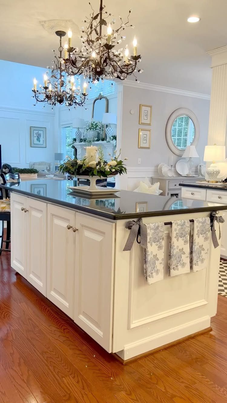 Two dark metal candle-style chandeliers hanging over a white kitchen island.