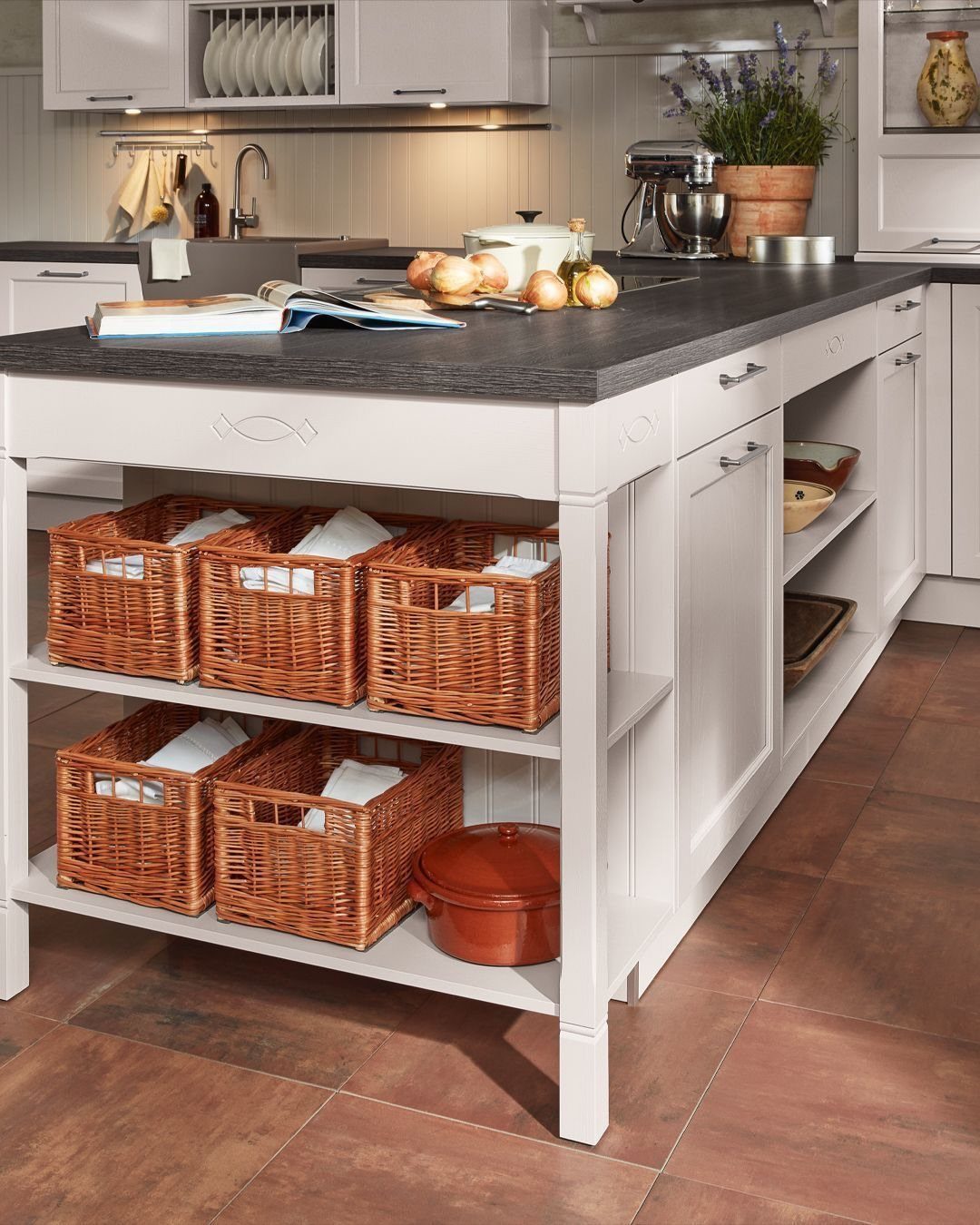 White kitchen island with open shelving containing several woven wicker storage baskets.
