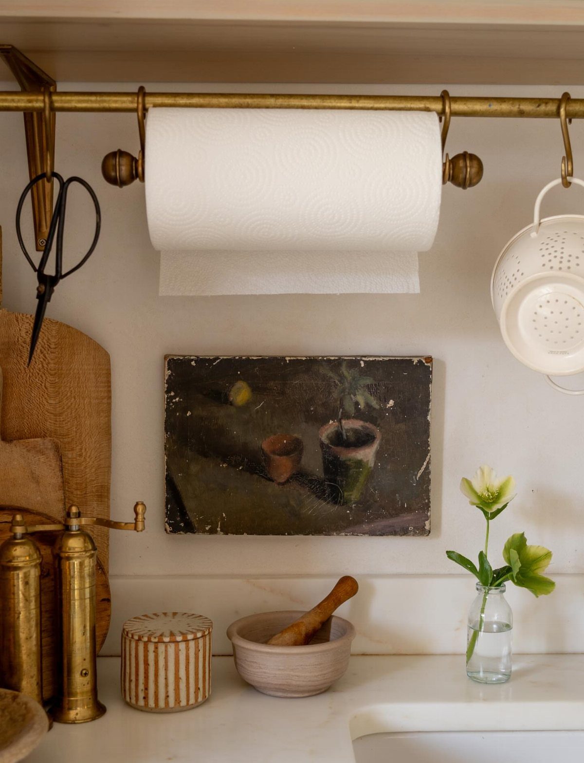 Kitchen counter with brass accents, paper towels, mortar and pestle, and a small floral arrangement.
