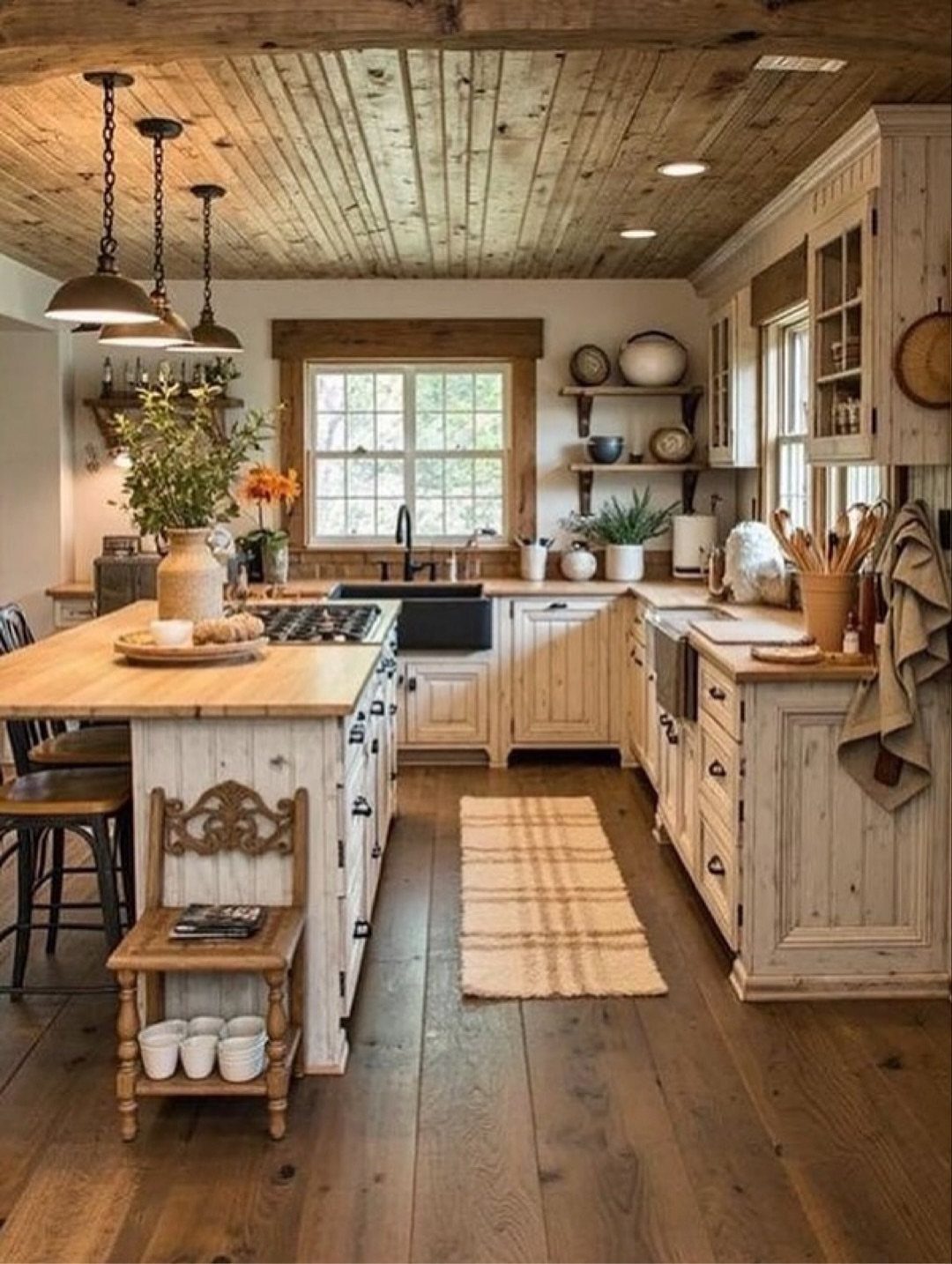 A rustic farmhouse kitchen with wooden cabinets, a large island, and a plank wood ceiling.