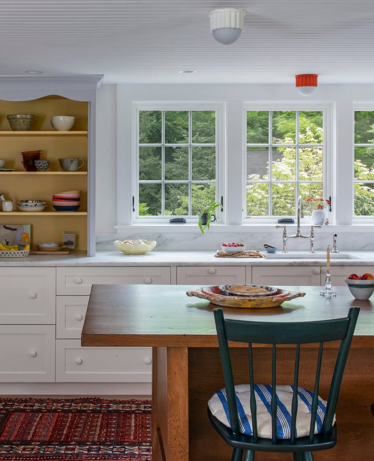 White beadboard ceiling above a bright kitchen with wooden island and large windows.