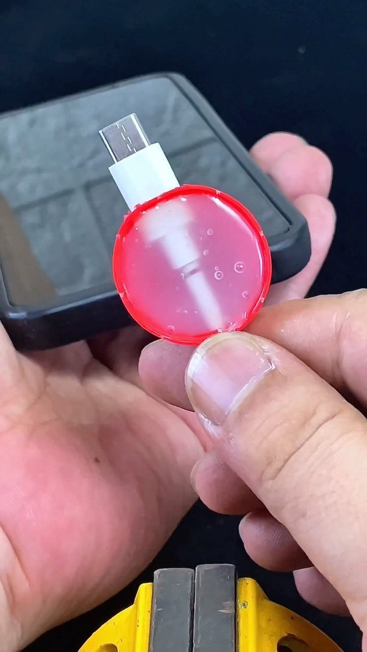 Hands holding a USB connector protected by a red circular material.