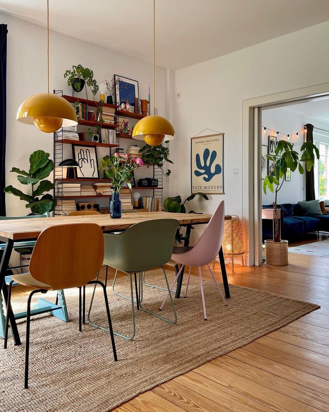 Various colorful and uniquely styled dining chairs arranged around a wooden table in an eclectic room.