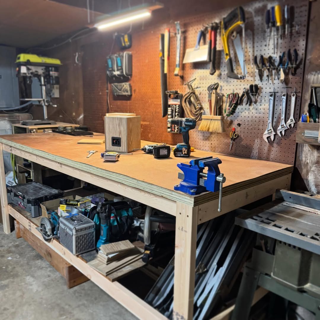A wooden workbench with a blue vise and power tools in a garage workshop.