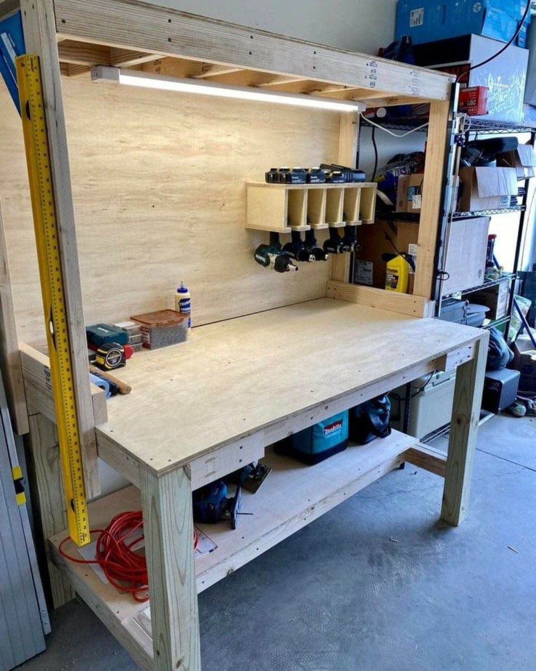 A sturdy wooden workbench constructed from plywood and timber with integrated lighting and tool storage.
