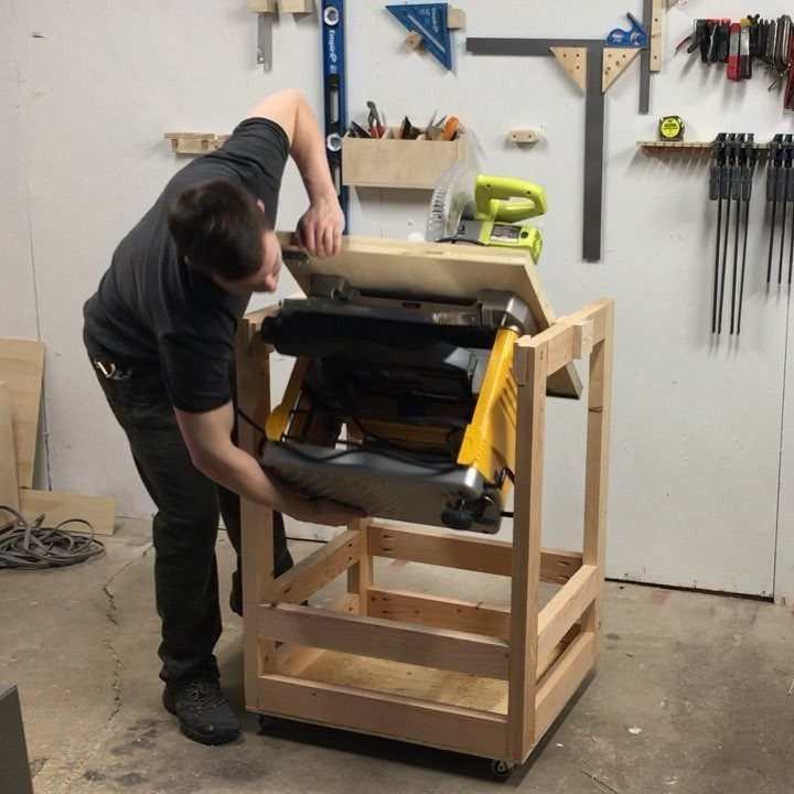 A man adjusting a yellow power tool mounted on a wooden flip-top workbench in a garage.