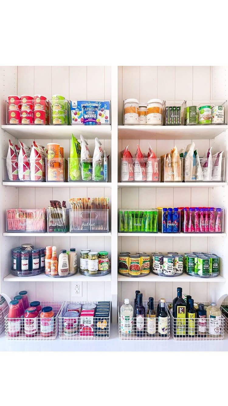 Organized white pantry shelves filled with various colorful food items, cans, and snacks in clear containers.