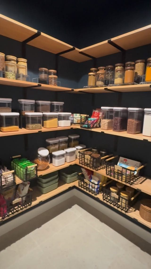 Wooden pantry shelves filled with various glass jars and organized food containers against a dark wall.
