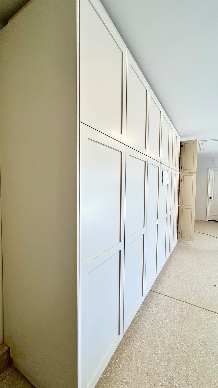 Tall white custom storage cabinets installed along a clean garage wall.