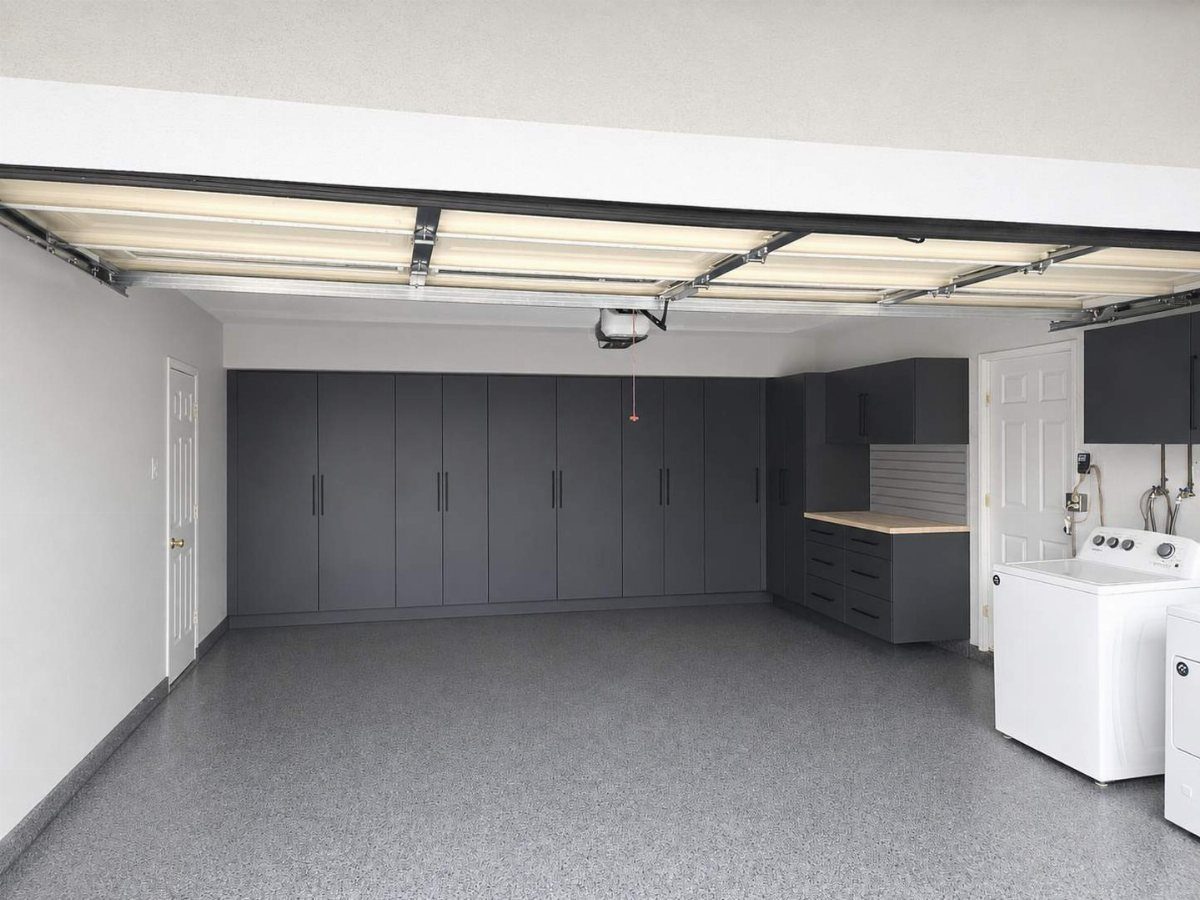 Dark gray garage cabinets installed along a clean white wall in a spacious garage.