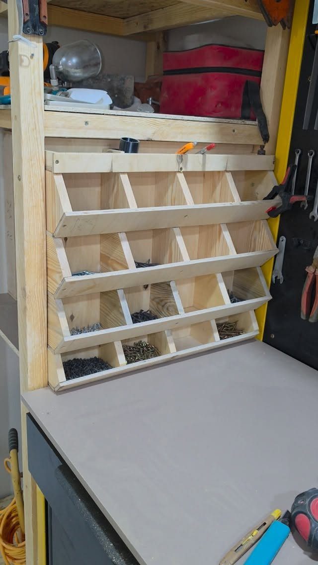 Wooden DIY organizer with multiple compartments filled with various small metal screws on a workbench.