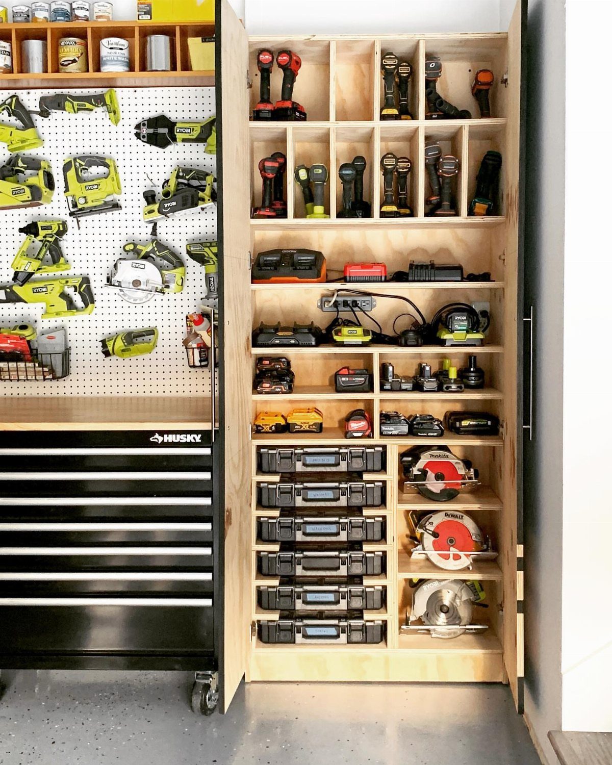Wooden garage shelving unit and pegboard filled with various power tools and storage cases.