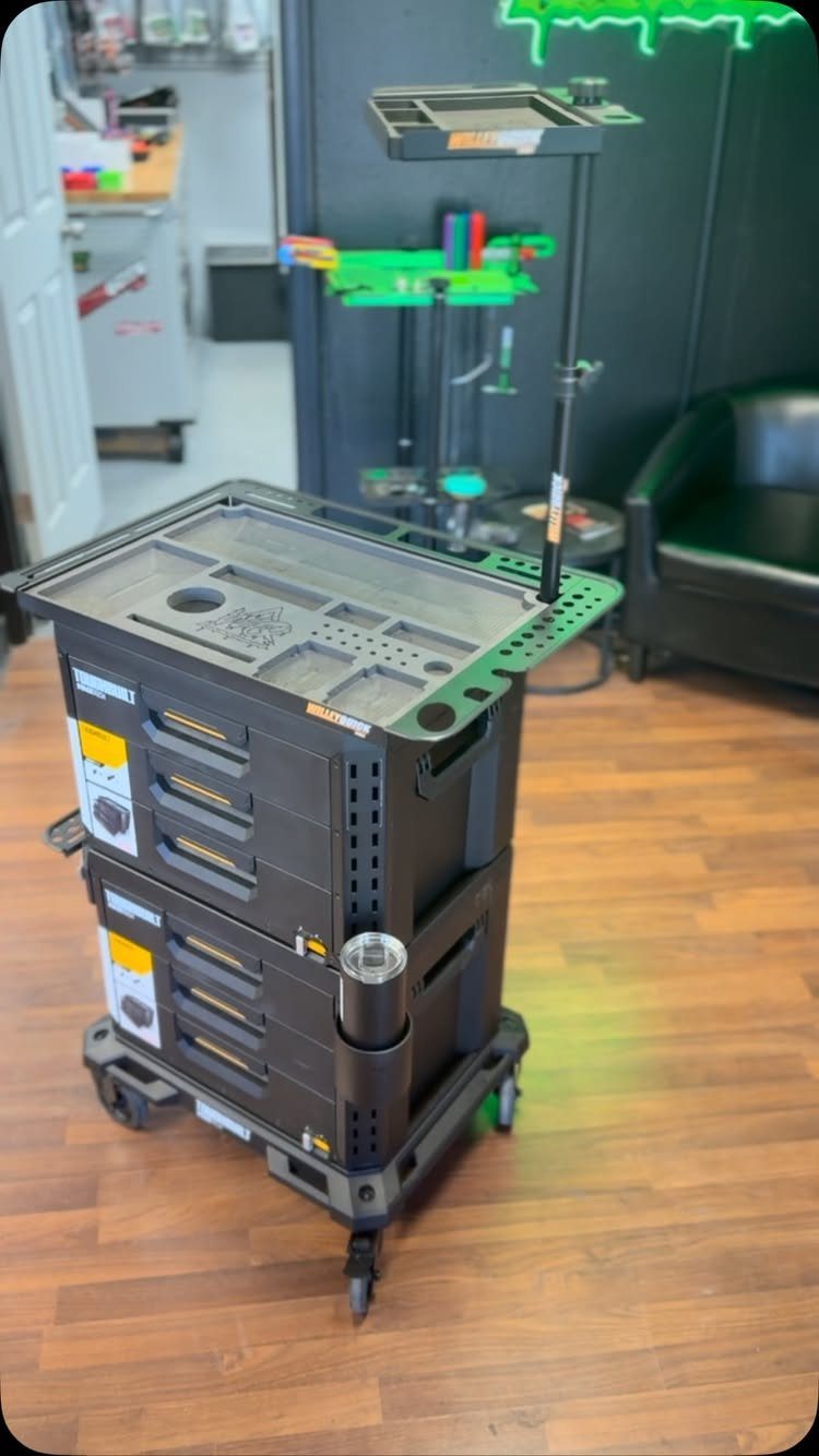 A black plastic rolling tool cart with multiple storage compartments on a wooden floor.