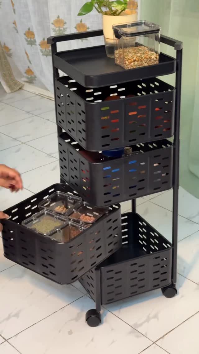 A black four-tier rolling cart with storage baskets being used to organize items on a tiled floor.