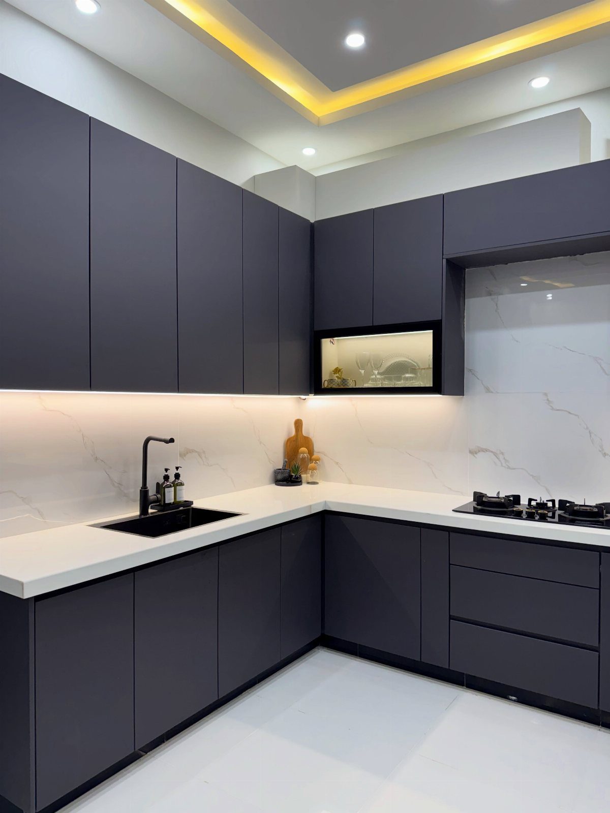 Modern L-shaped kitchen featuring dark grey matte cabinets and white marble countertops.