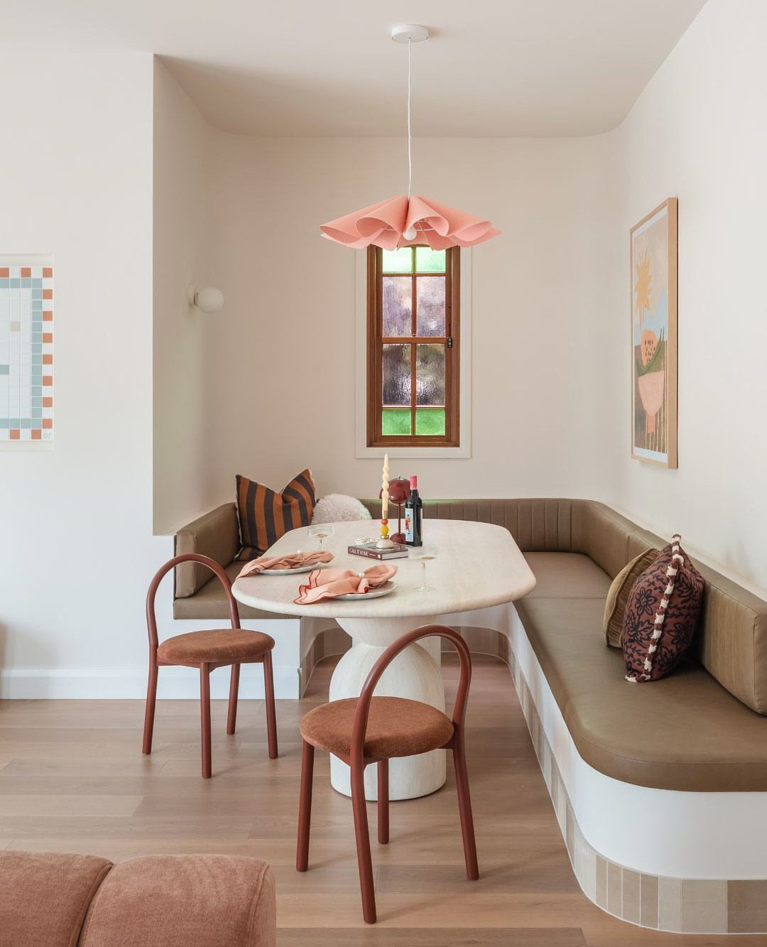 Built-in banquette seating with a marble table and terracotta chairs in a bright dining nook.