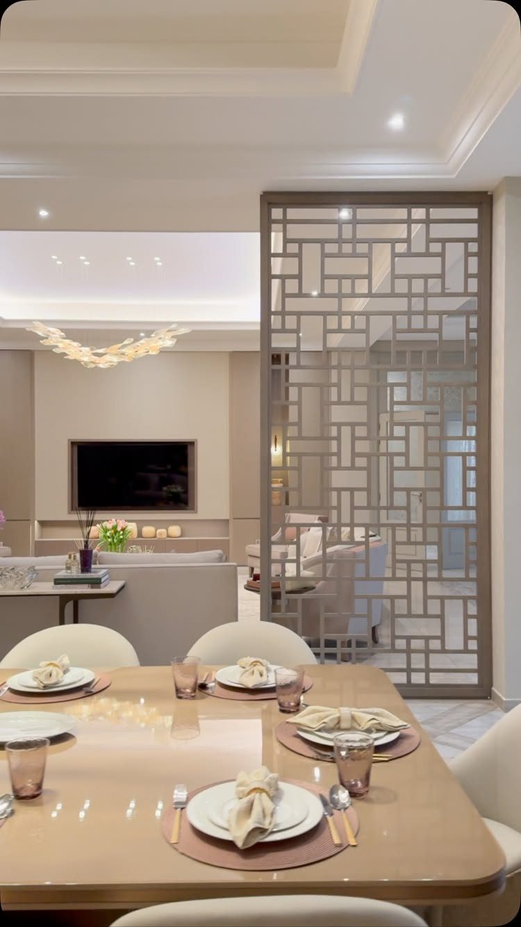 A dining table set for a meal overlooking a modern living room with a geometric divider.