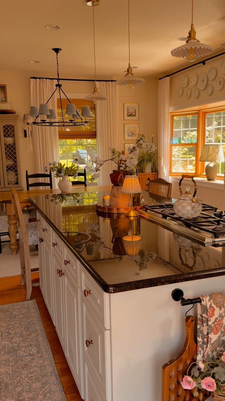 A large kitchen island with a dark countertop and built-in stovetop separating the kitchen and dining area.