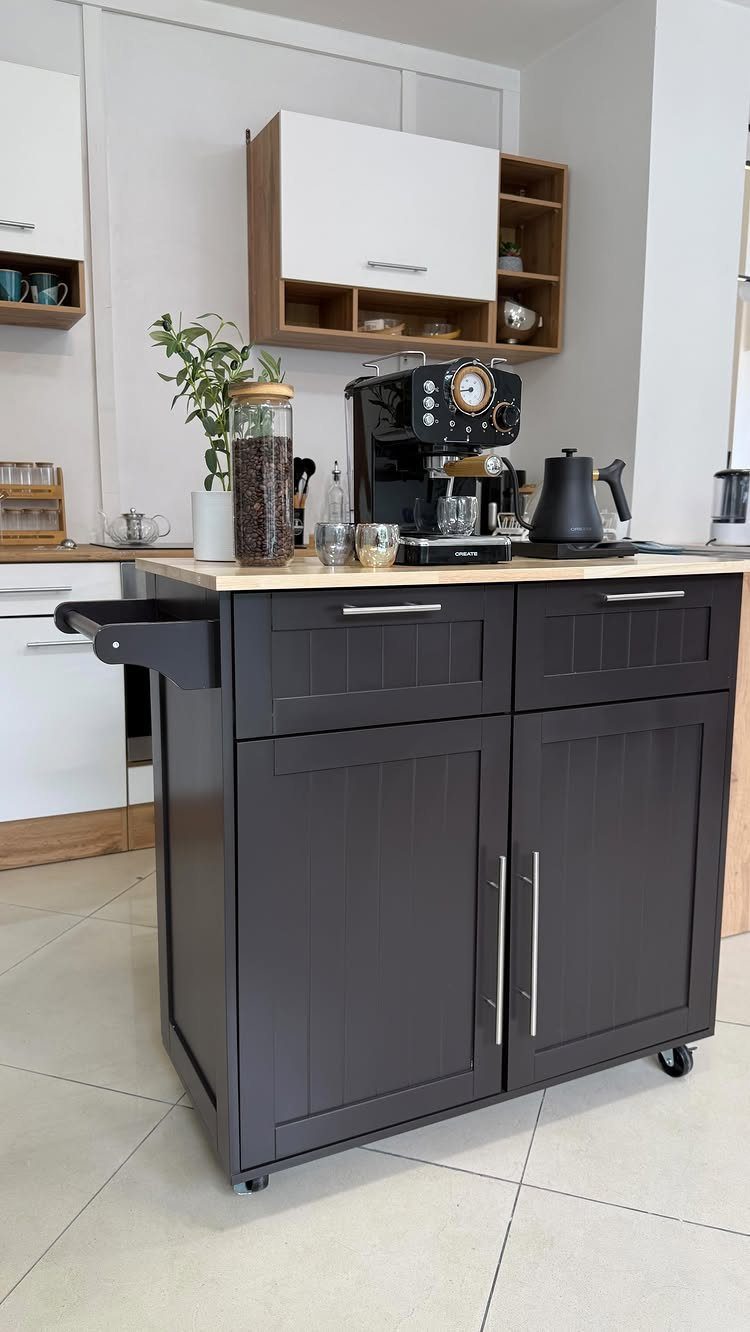A dark grey kitchen rolling cart with a wooden top holding a coffee machine and plant.