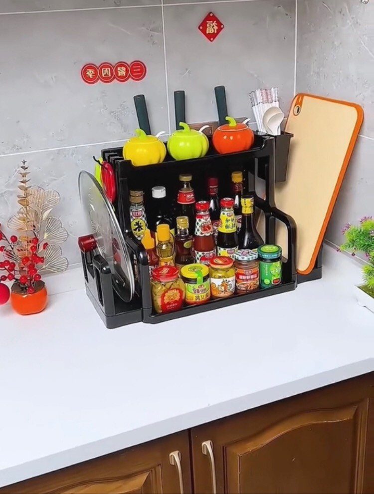 Black tiered countertop organizer holding various condiment bottles and jars on a white kitchen counter.