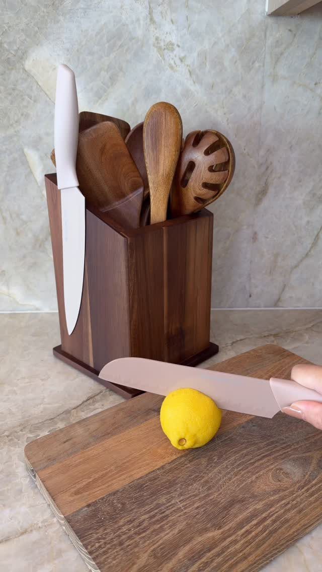 Wooden utensil holder filled with various wooden cooking spoons on a marble countertop.
