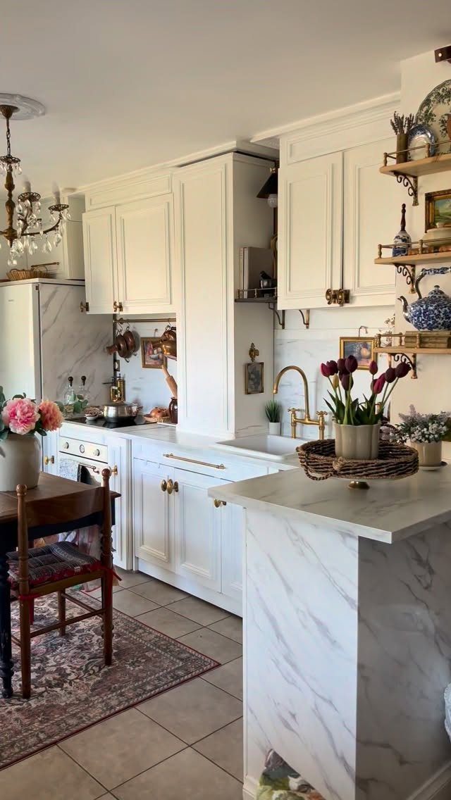 White kitchen cabinets with marble countertops, gold hardware, and a vintage white stove.