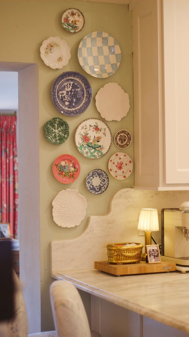 Decorative patterned ceramic plates arranged in a gallery style on a light green kitchen wall.