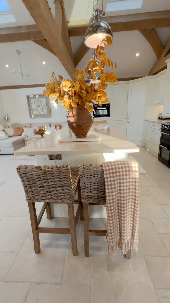 Two wicker bar stools with wooden legs positioned at a white kitchen island.