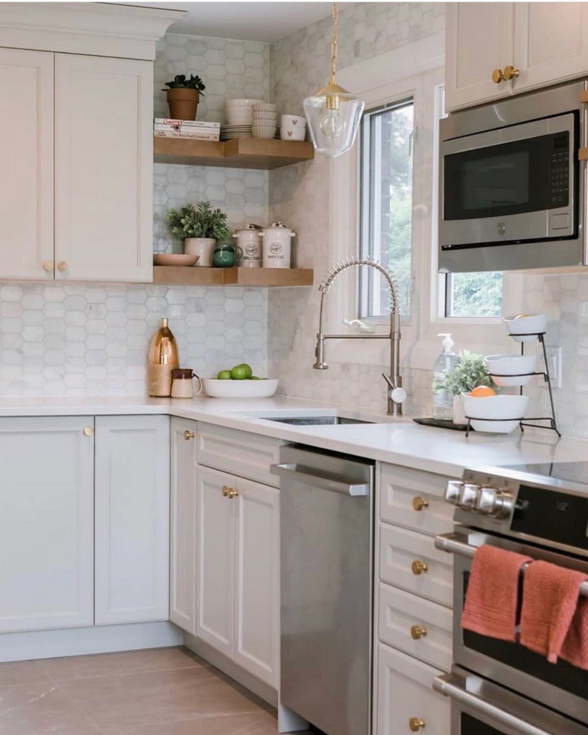 A bright kitchen with white cabinets, wooden shelves, and a glass pendant light hanging above the sink.