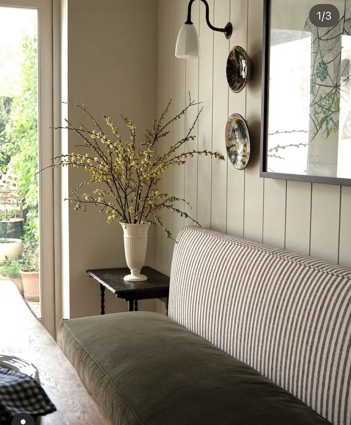 Striped banquette seating with a gray cushion next to a vase of flowering branches.