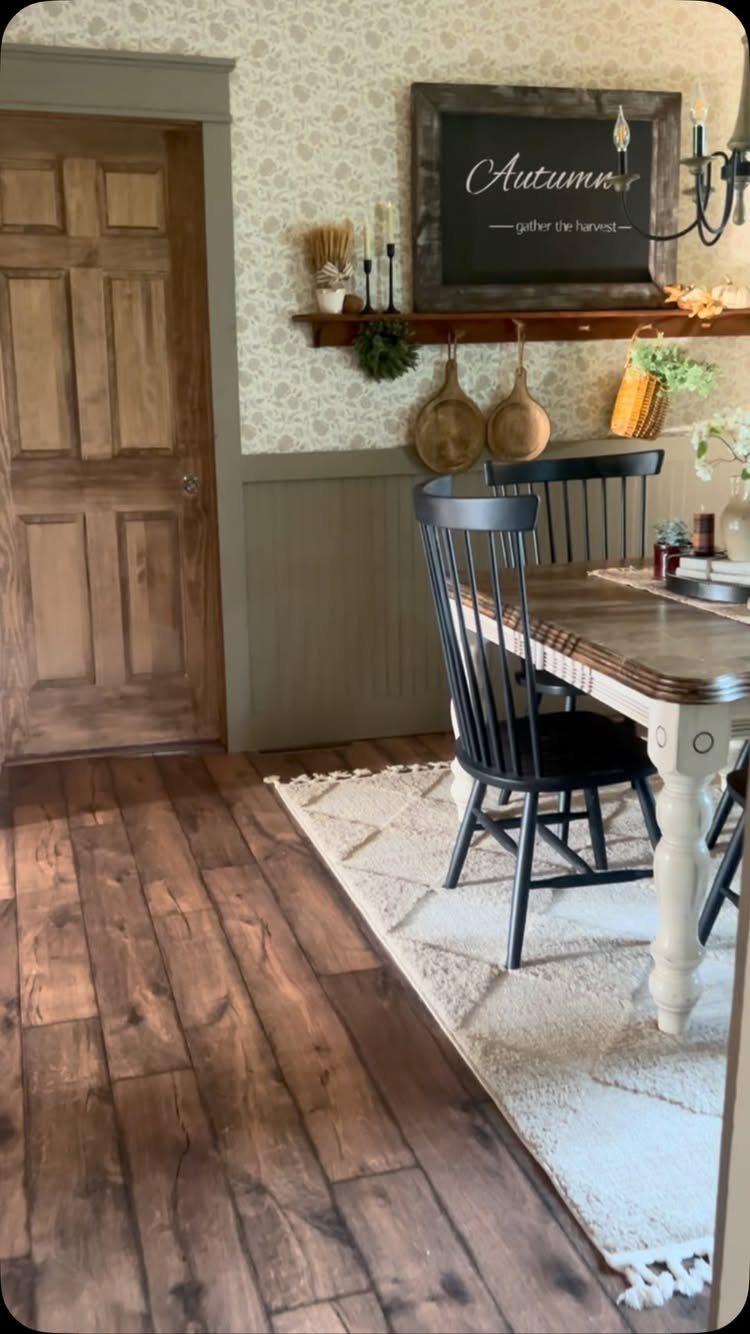 Dining room with patterned wallpaper, wooden table, black chairs, and decorative wall shelf.
