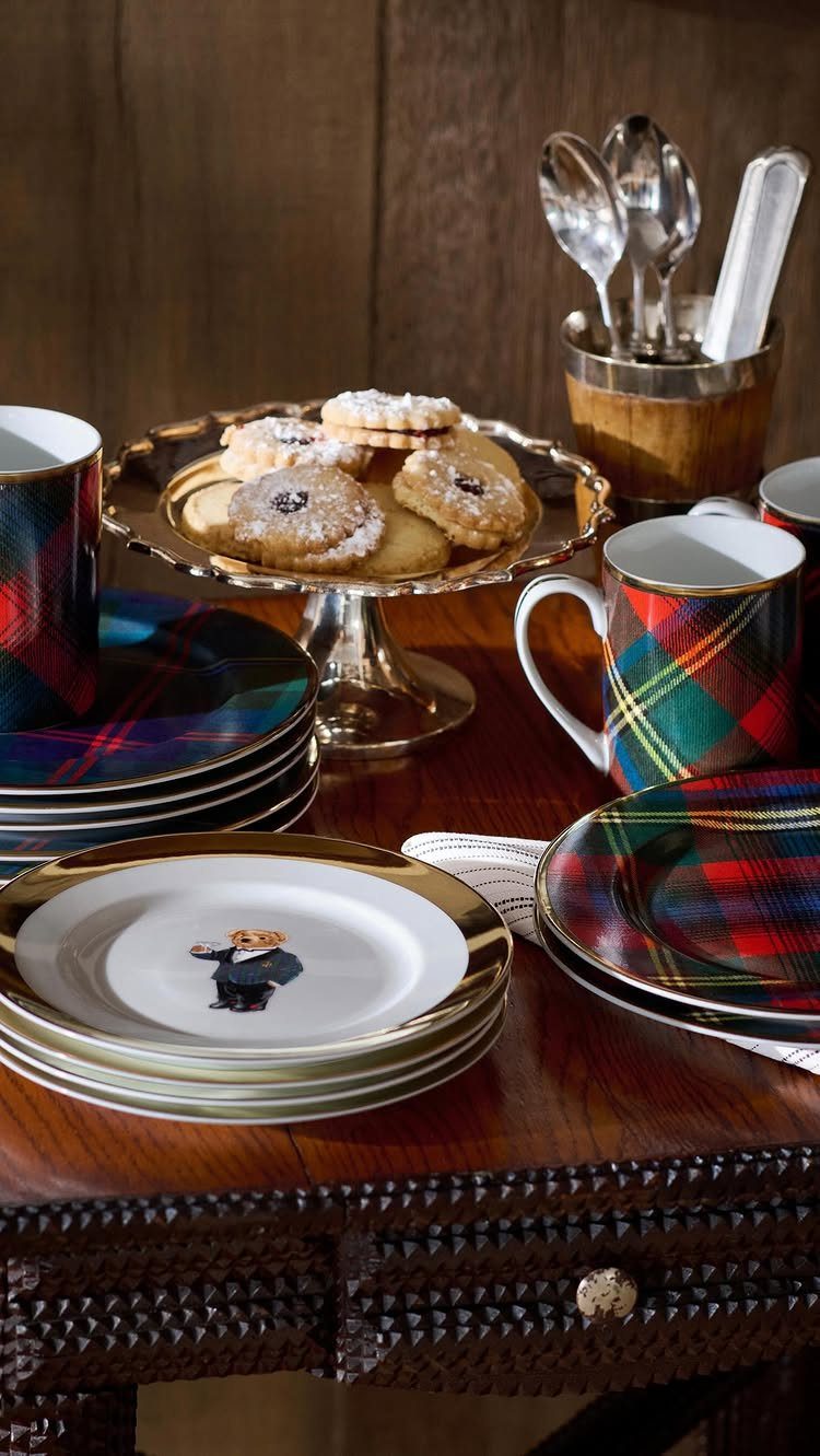 Plaid patterned plates and mugs arranged with cookies on a gold stand on a wooden table.