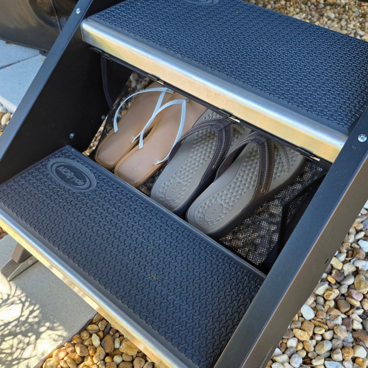 Black step stool with an open compartment containing sandals stored in a mesh net.