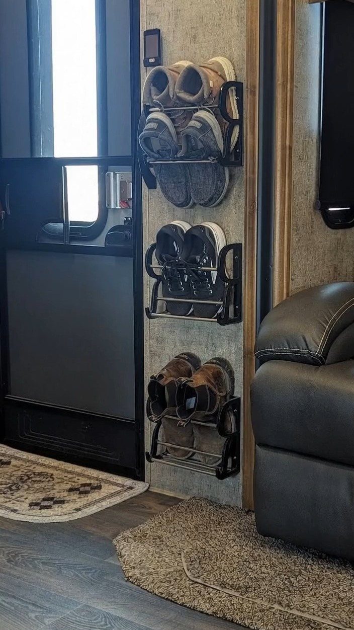 Black metal wall-mounted shoe racks holding several pairs of shoes inside a camper interior.