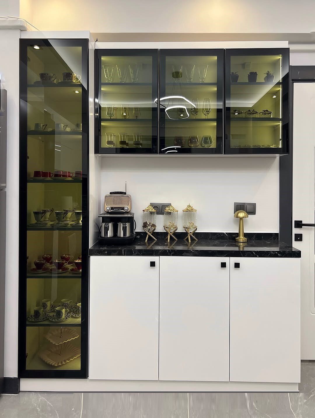 Modern kitchen cabinets with illuminated glass doors displaying various glassware and dishes.