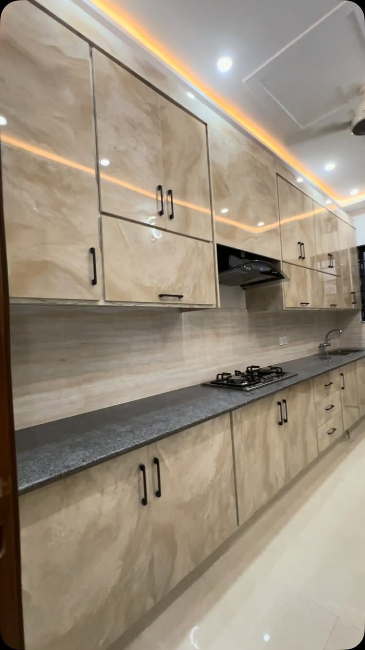 High-gloss marble patterned kitchen cabinets with black handles and warm LED lighting.
