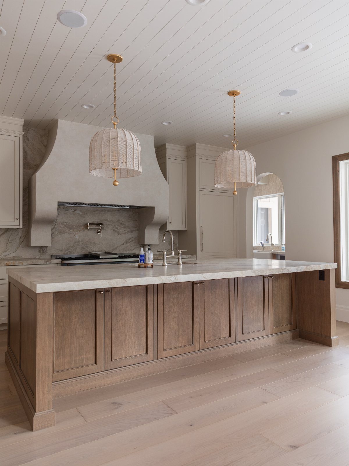 A large wooden kitchen island with a white marble countertop in a bright, modern kitchen.