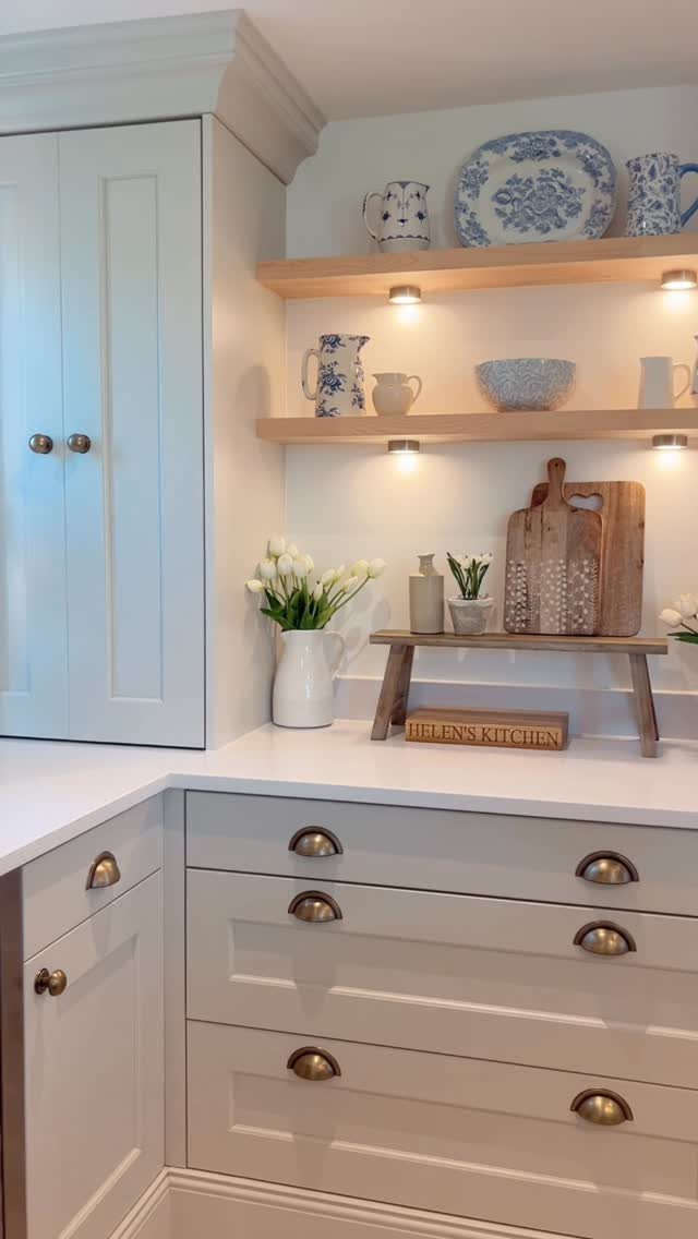 Light blue kitchen cabinets with wooden open shelving displaying blue and white patterned ceramic dishes.
