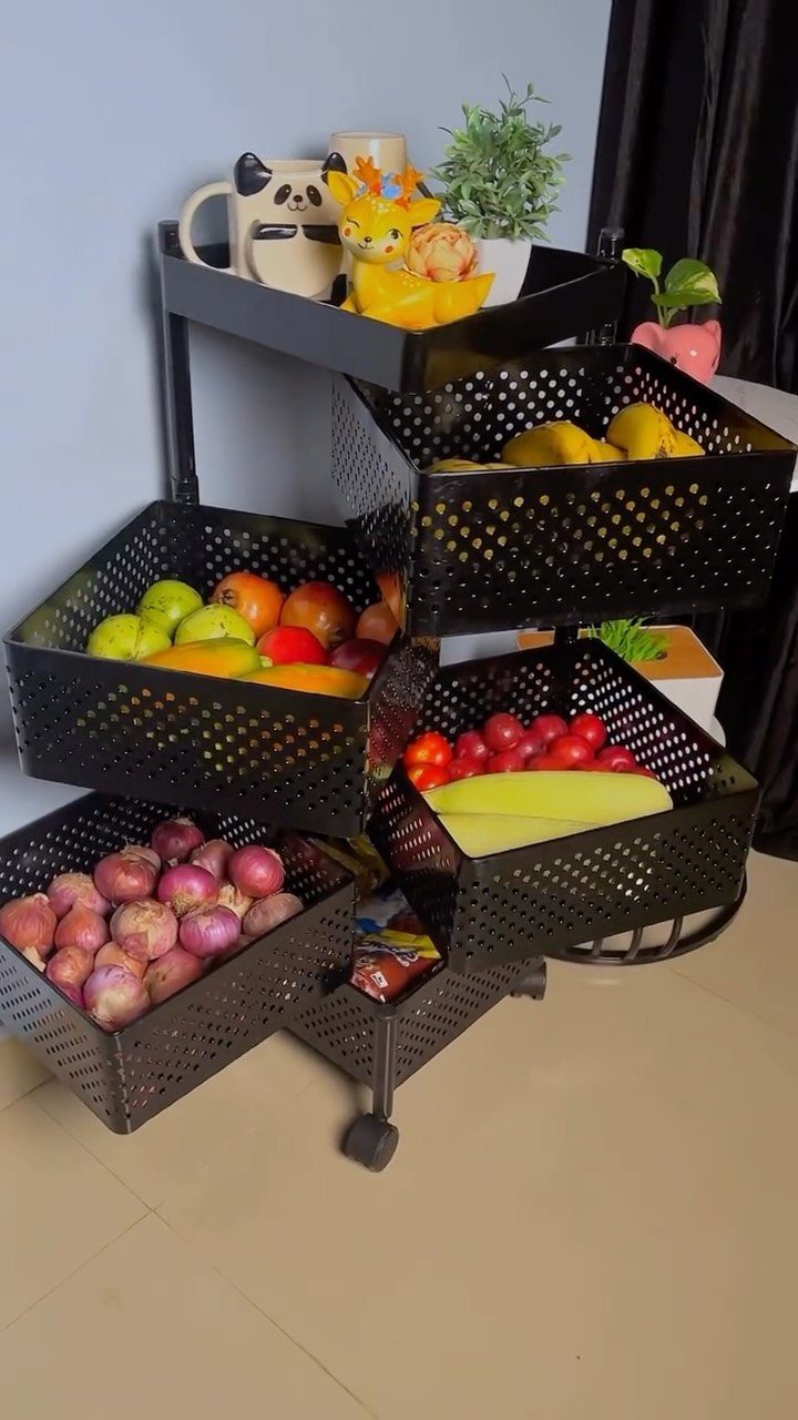 A black metal rolling cart with perforated baskets filled with various colorful fruits.