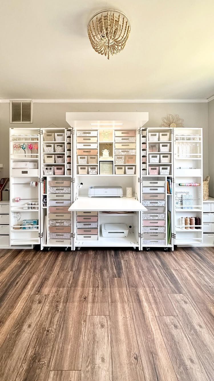 White organizational shelving unit filled with various storage containers and craft supplies in a bright room.