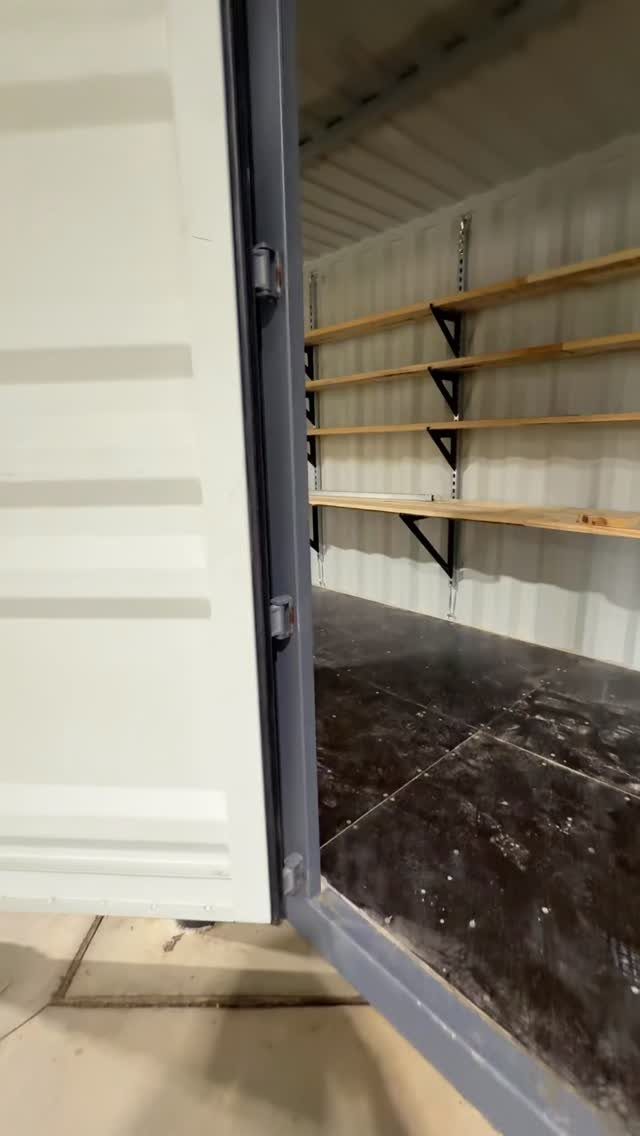 Wooden shelves with black metal brackets mounted on the wall of an open storage container.