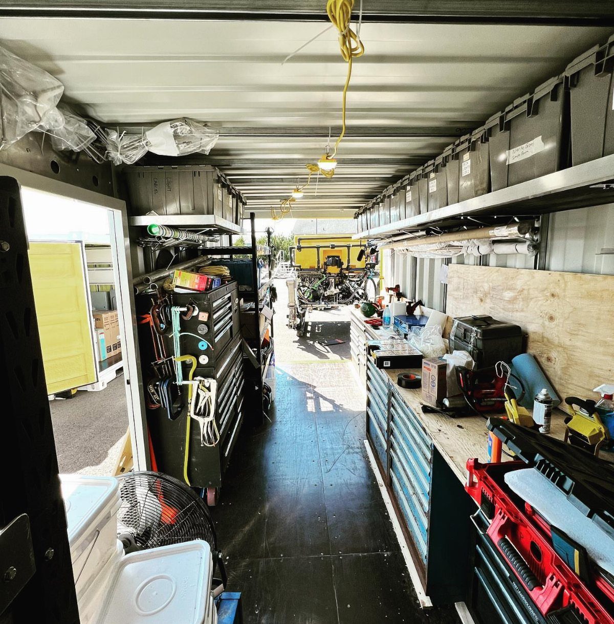 Interior of a mobile workshop with a long workbench and integrated storage bins.
