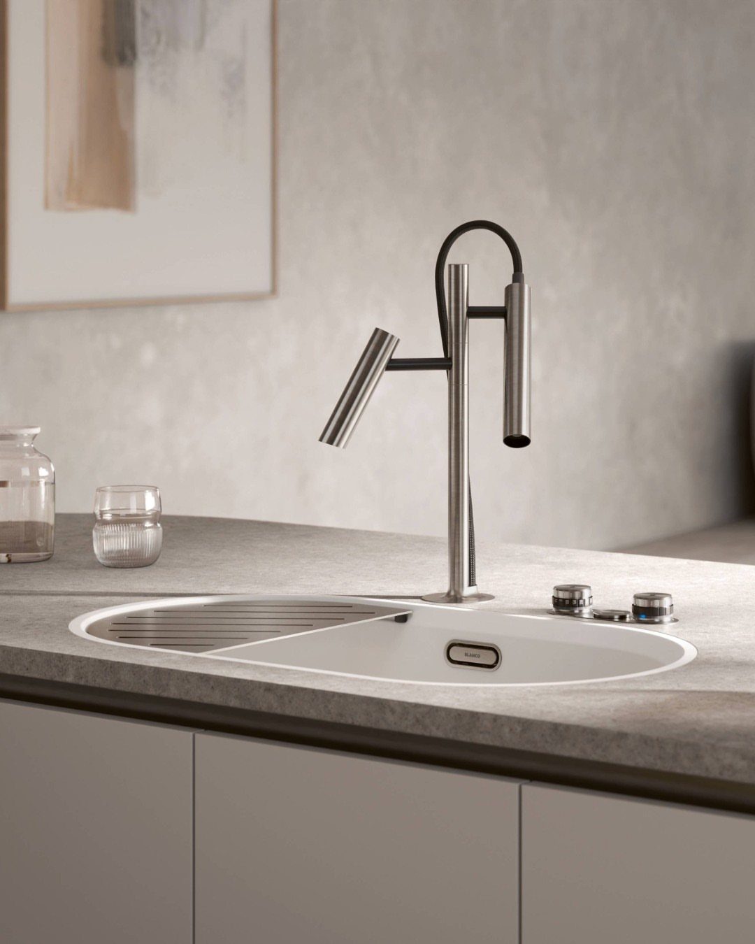 A modern brushed metal kitchen faucet installed over a white sink on a grey countertop.