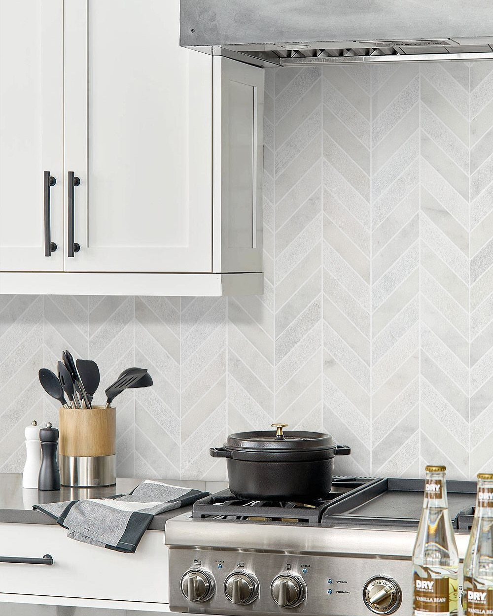 White marble tiles arranged in a chevron pattern on a kitchen backsplash.