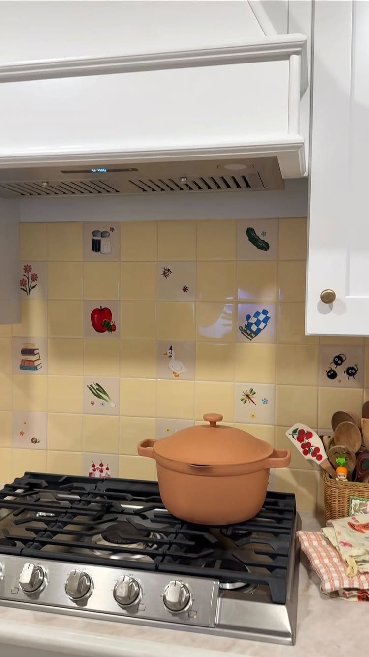 Hand-painted cream tiles with small fruit and vegetable illustrations on a kitchen backsplash.